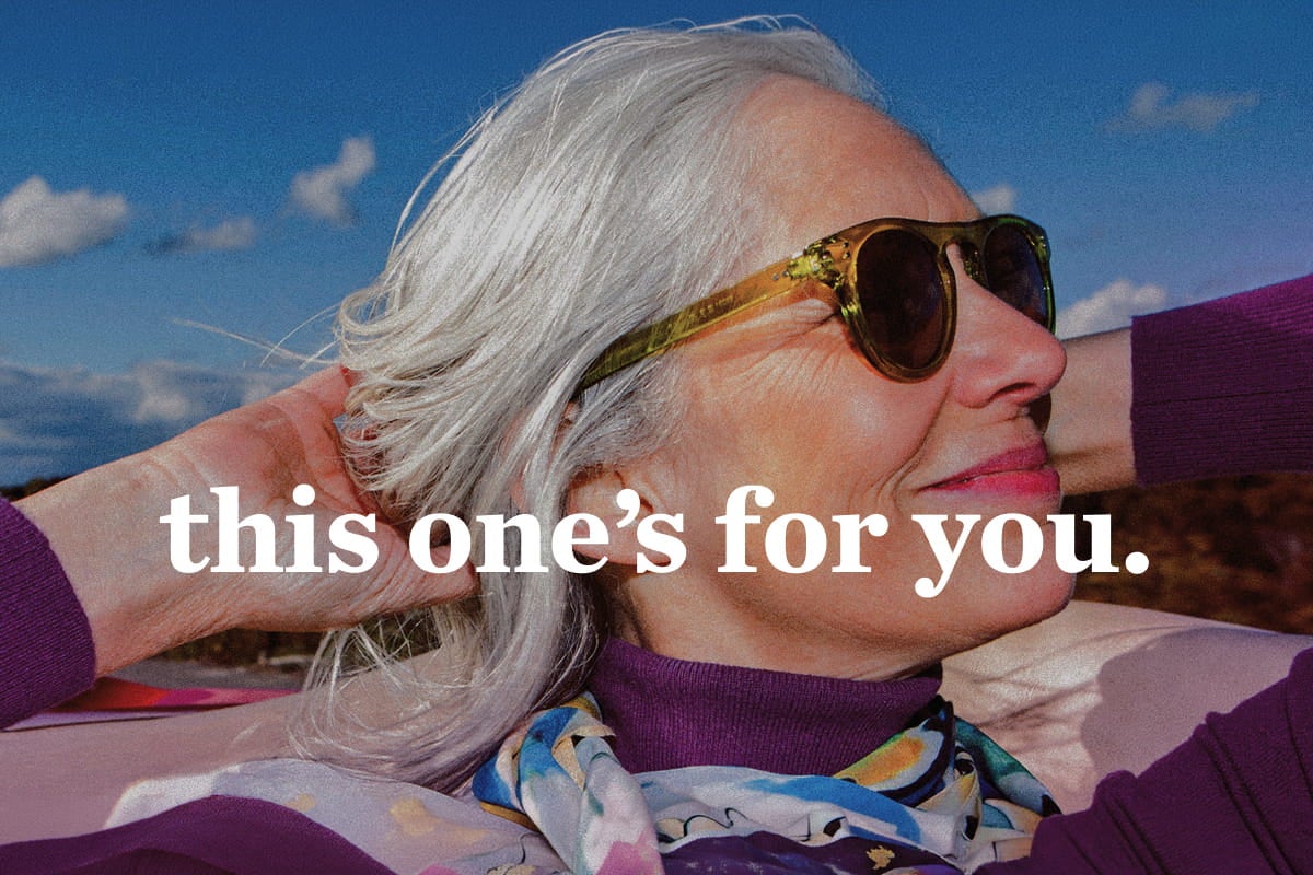 Gray-haired woman wearing sunglasses outdoors with the text, “this one’s for you.”