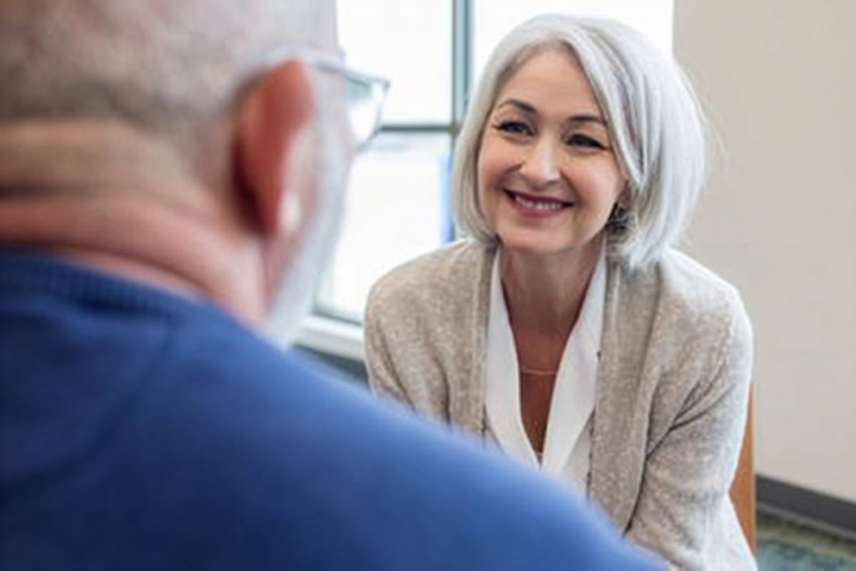 Woman smiling while speaking with a patient during a healthcare visit.