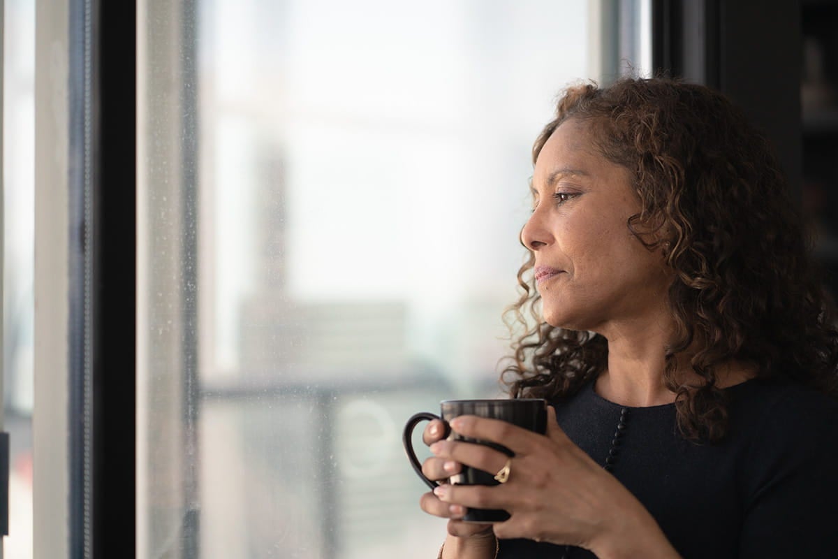 Woman looking out window; Breast specialists at Ascension Saint Agnes Hospital Cancer Institute deliver advanced care and support.