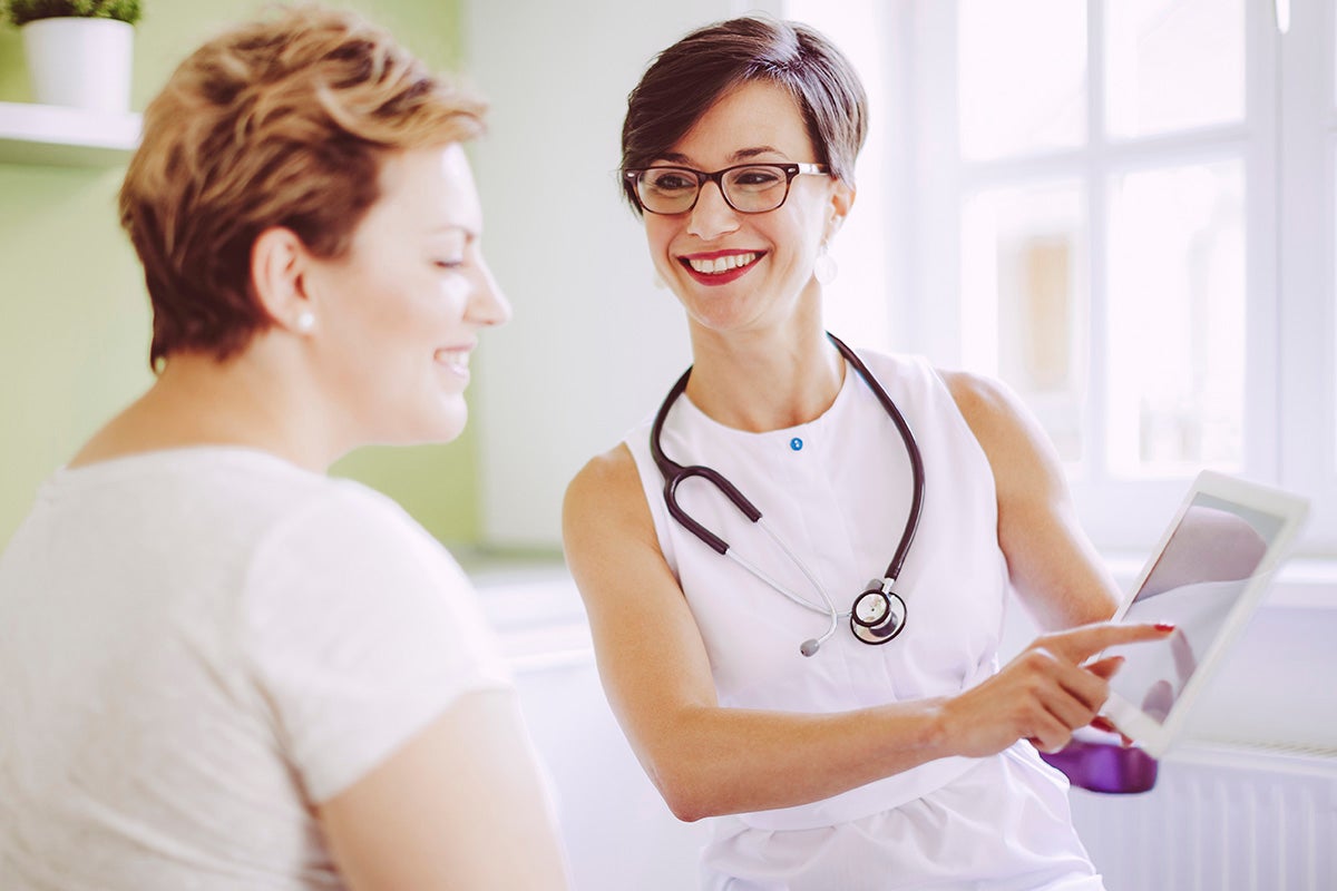 Provider showing medical information on a tablet to a patient during a visit.