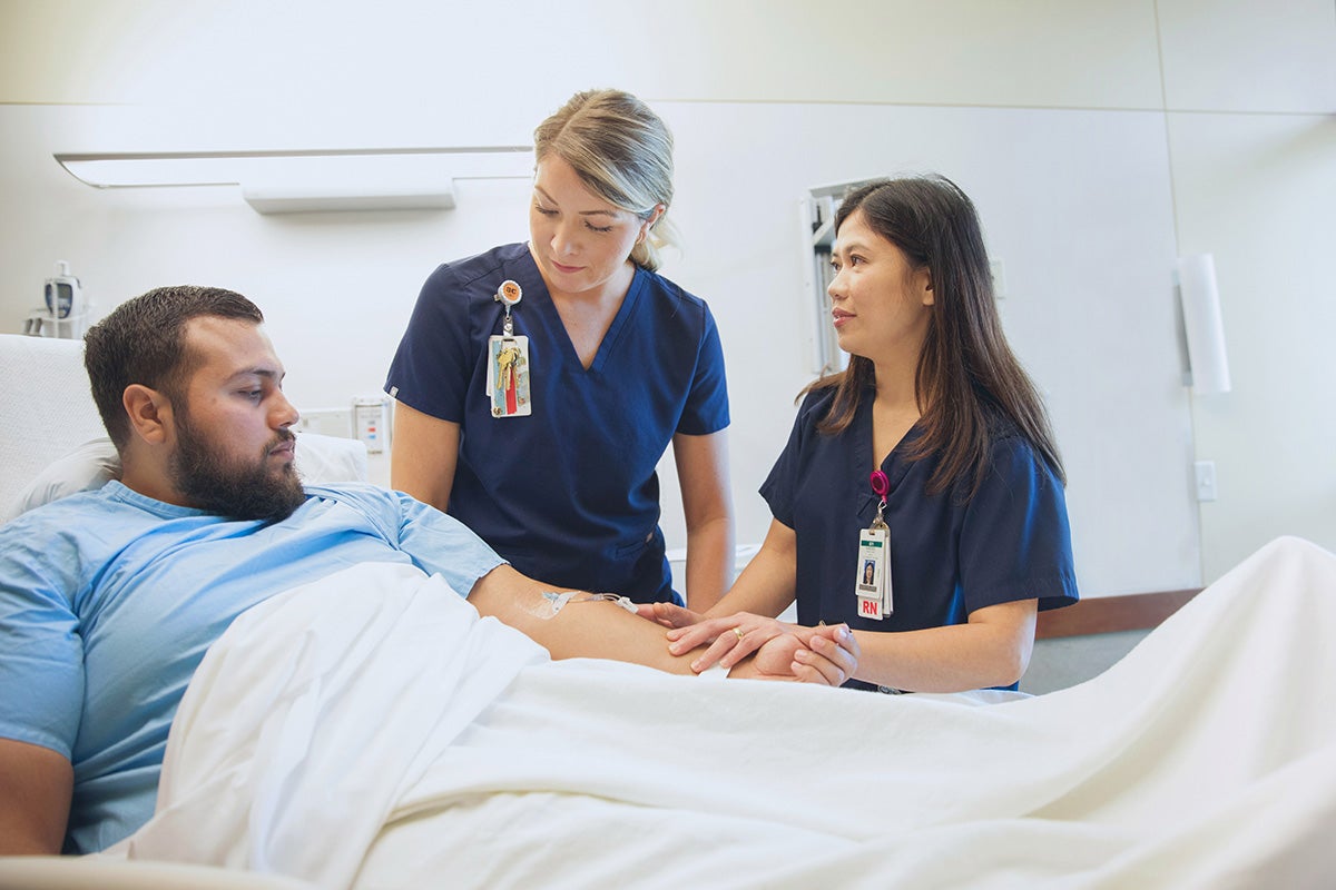 Male patient in hospital bed having a conversation with providers