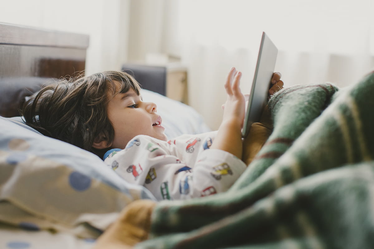 Child in bed playing on an iPad
