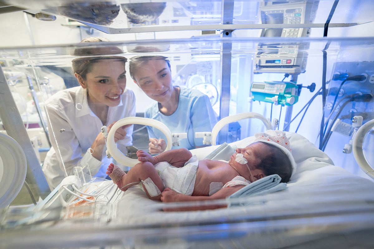Mother and nurse peer into a neonatal intensive care unit incubator at Ascension Via Christi in Wichita, Kansas.