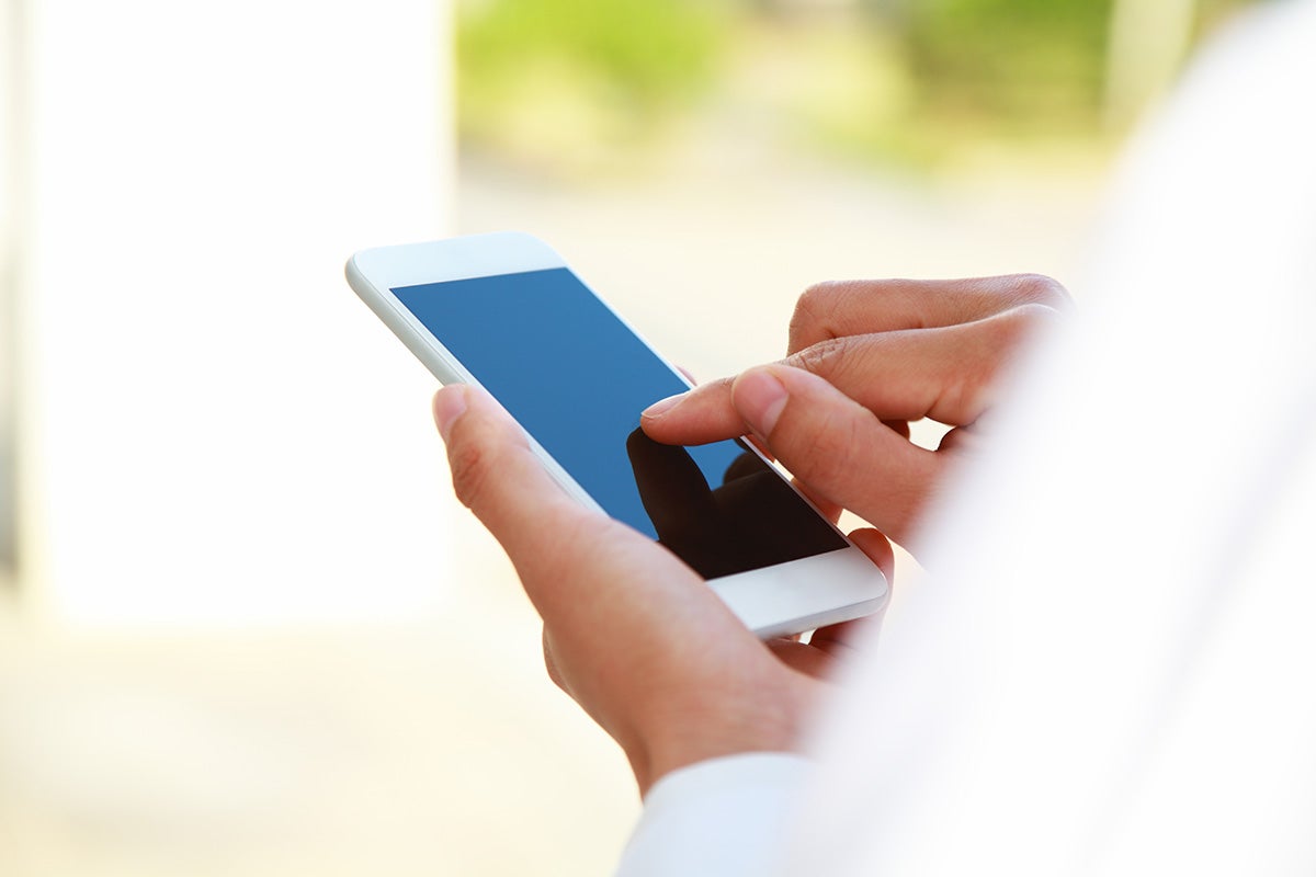 Person using a smartphone by tapping on the screen with one hand.
