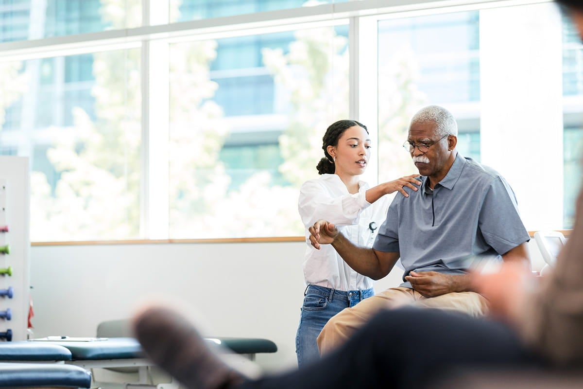 Female physical therapist manipulates a man's injured shoulder.