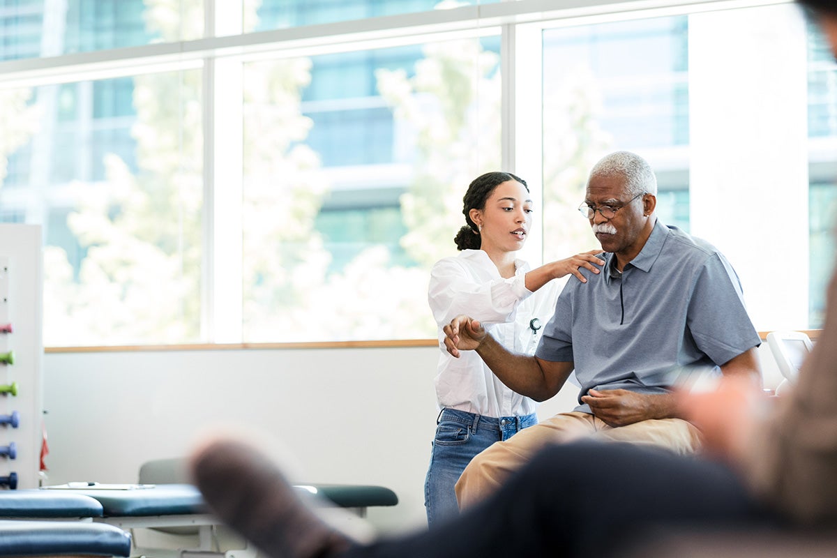 Female physical therapist manipulates a man's injured shoulder.