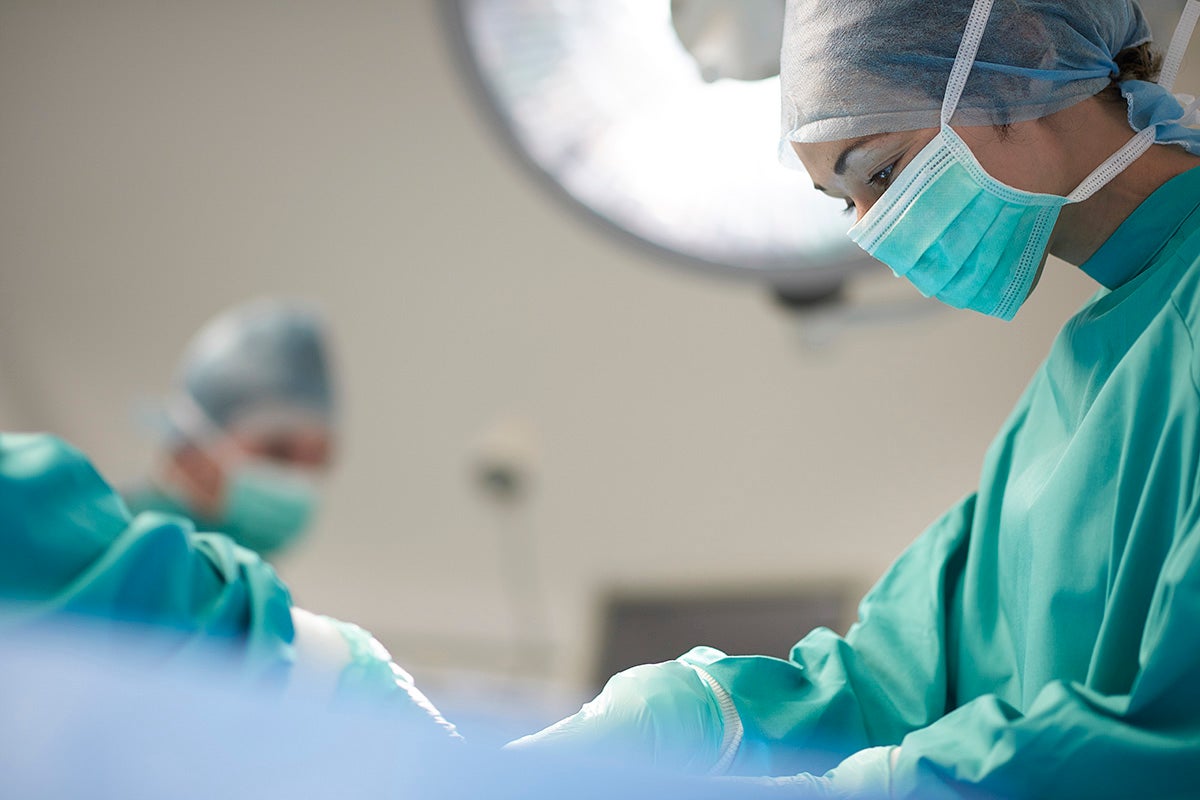 Surgeon performing a procedure in an operating room with another clinician assisting.