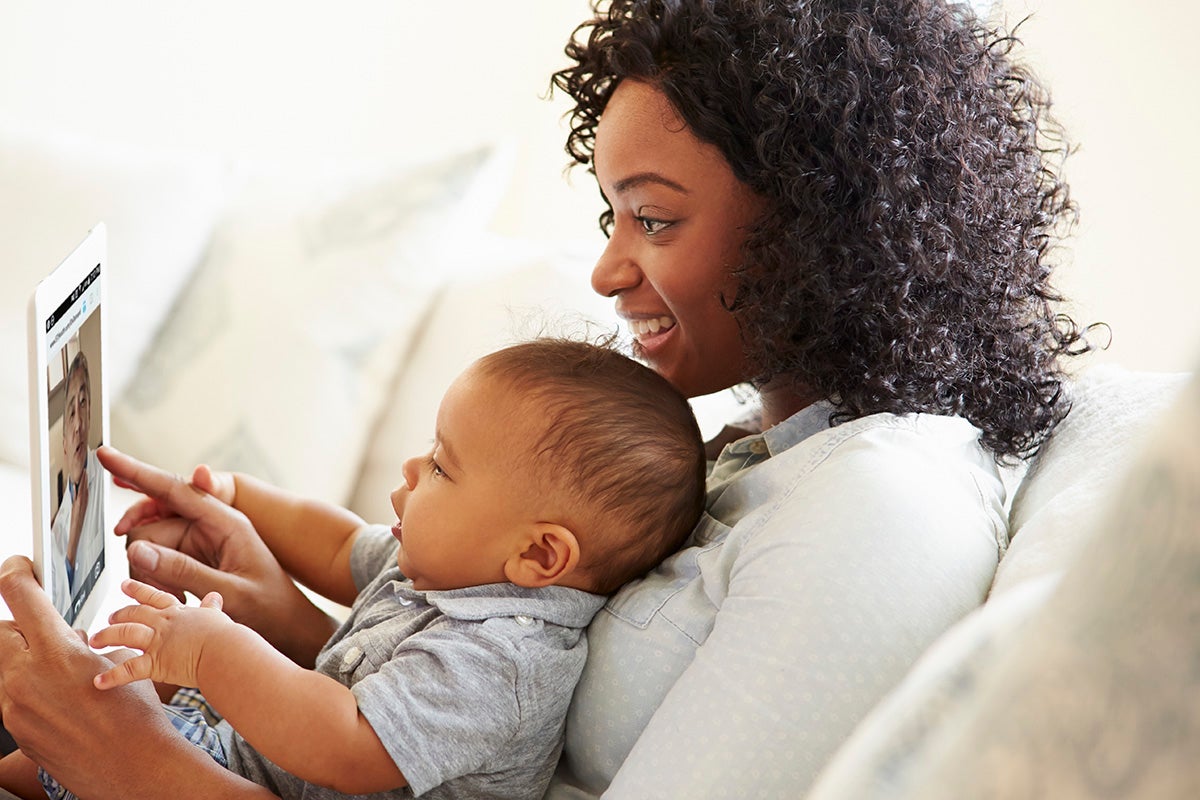 Parent and baby looking at a tablet, as if they’re about to schedule virtual care.