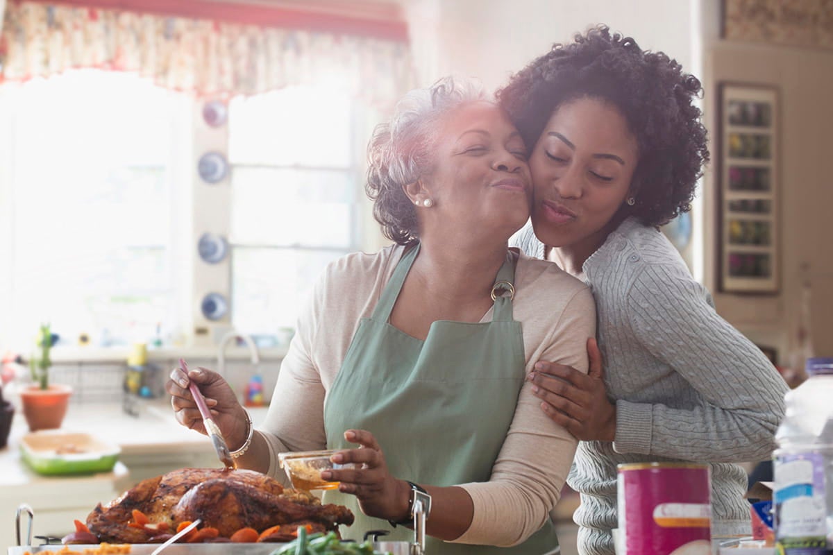 Mother and daughter cooking together in kitchen.