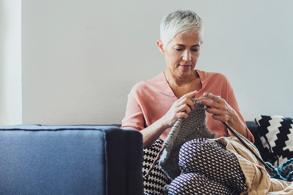 Woman knitting on the couch.