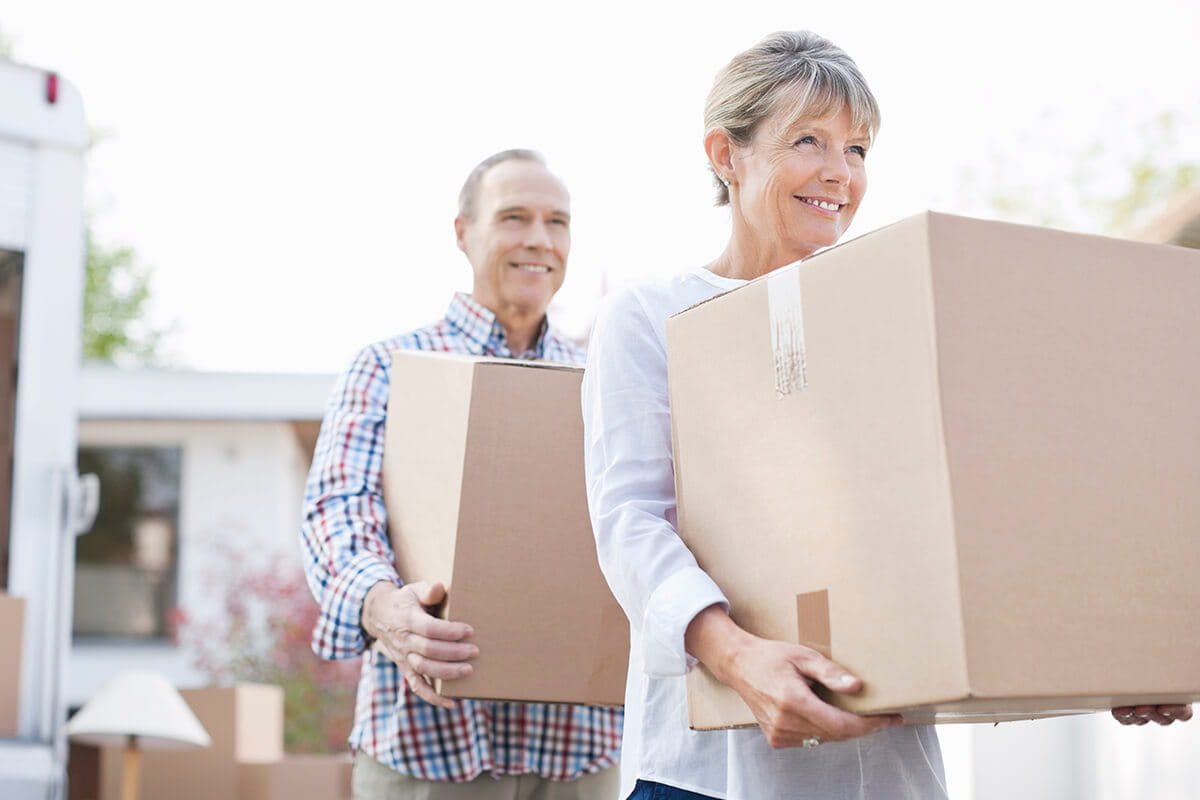 Older couple carrying moving boxes