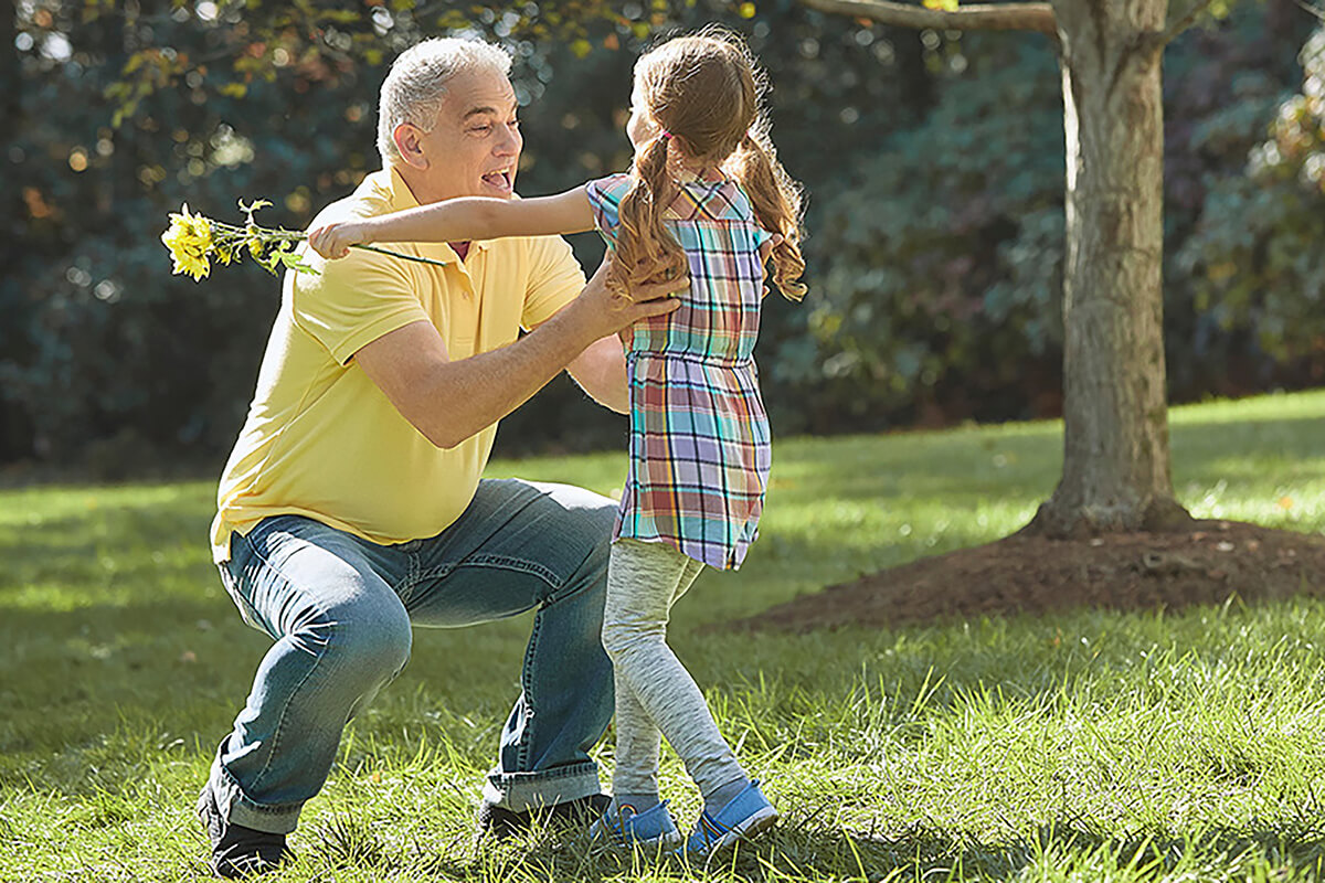Grandfather playing outside with his granddaughter after getting orthopedic care at an Ascension site of care.