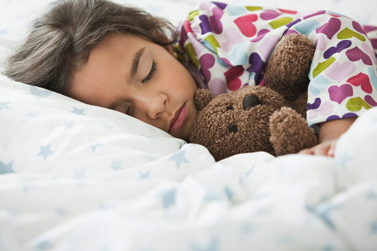 Girl sleeping with teddy bear.