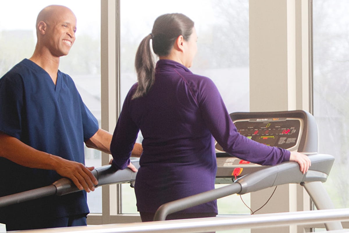 Patient running on a treadmill with a physical therapist