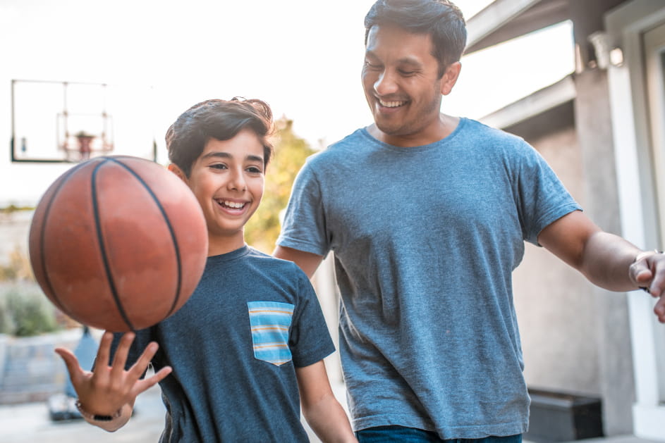 Man playing basketball with teen son.