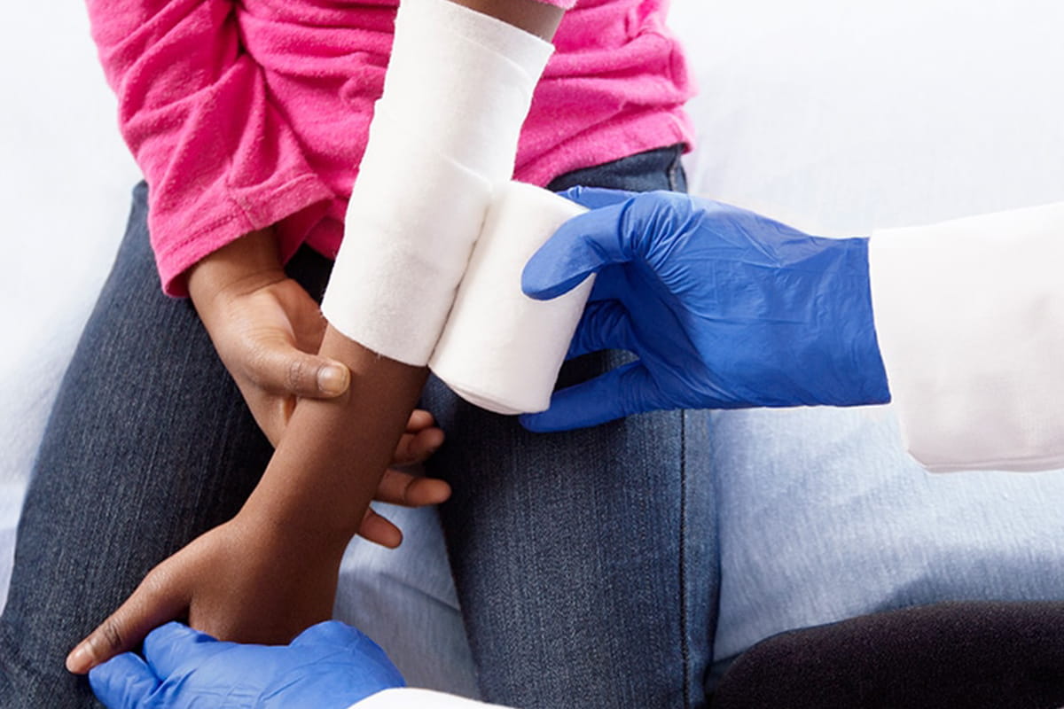 Doctor wrapping a girl's arm with a bandage 