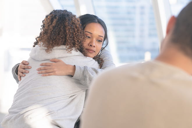 Woman embraces a loved one as they meet with a behavioral and mental health therapist at an Ascension site of care. 