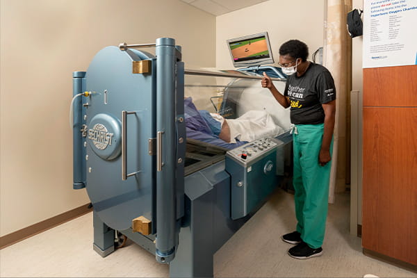 A caregiver at the Wound Healing and Hyperbaric Therapy clinic checks in on a patient