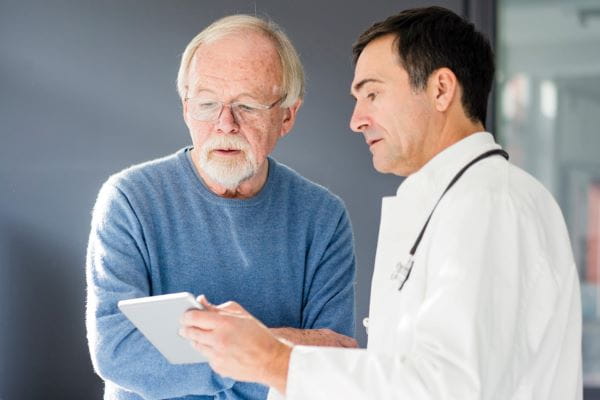 male doctor talking to older while male patient about structural heart valve care