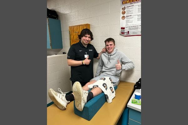 Athletic trainer Keenan Begley giving rehab care to high school senior Brody, who nominated Keenan for Most Valuable Educator. 