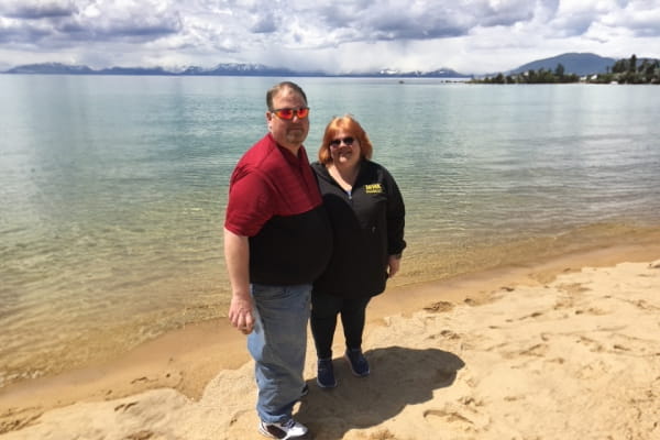 Married couple pose by the lake pre-bariatric surgeries. 