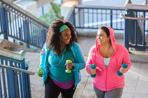 Two women exercising on stairs holding hand weights