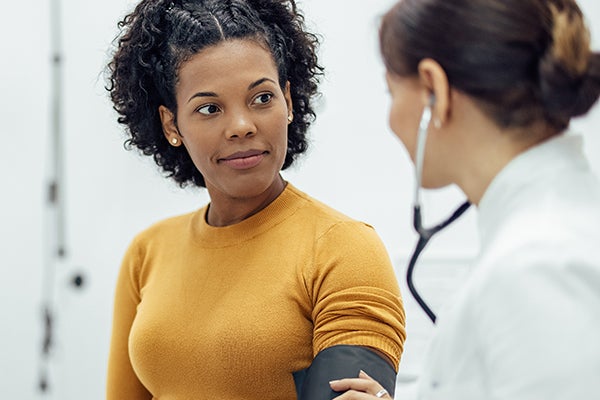 Woman with blood pressure cuff on her arm and provider with a stethoscope take blood pressure