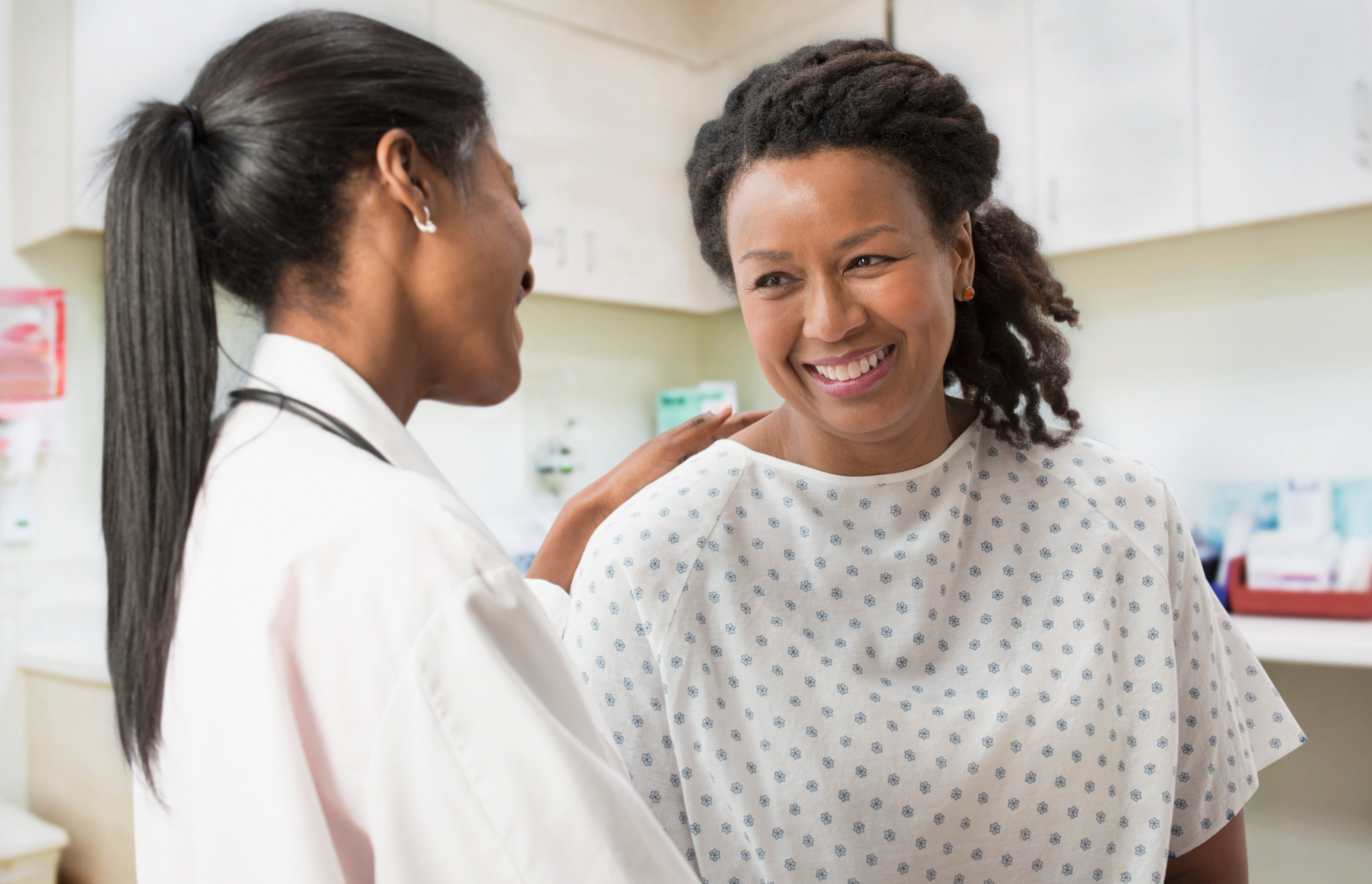 Doctor speaks with a smiling patient in a hospital examination room.