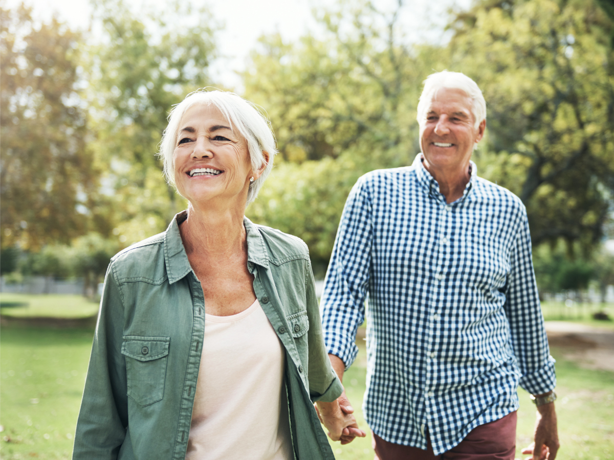 A couple walks hand in hand at the park.