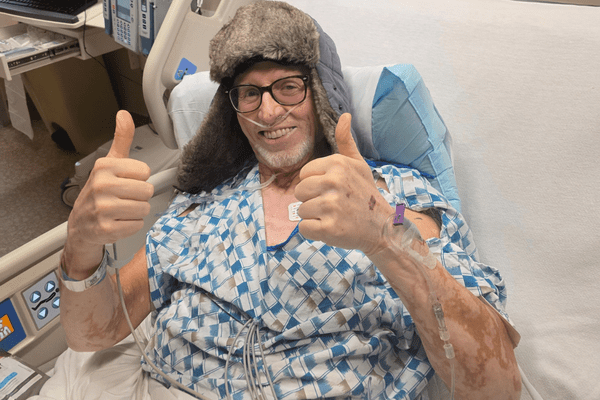 Roy Zacharias gives two thumbs up while recovering in his hospital bed after surgery.