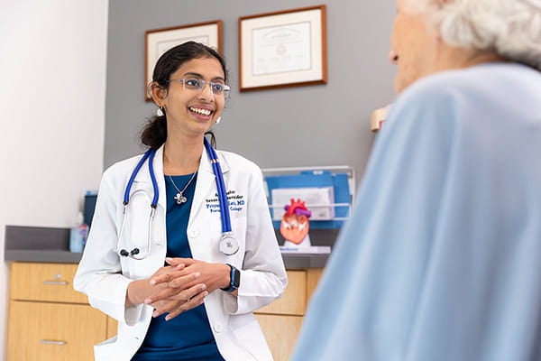 Priyanka Satish, MD, speaks with a patient in a clinic about their heart health.
