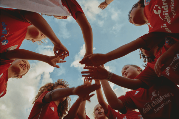 Youth soccer players gather in a team huddle before a game.