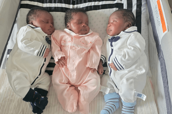 Triplets Osayui, Osayimwense and Osagiede Isokpunwu sleep side by side in a bassinet 
