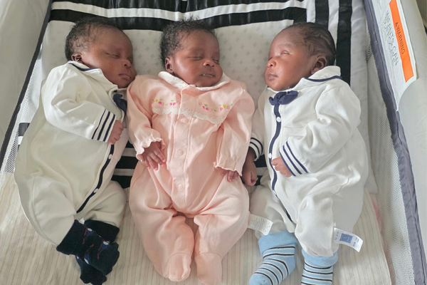 Triplets Osayui, Osayimwense and Osagiede Isokpunwu sleep side by side in a bassinet