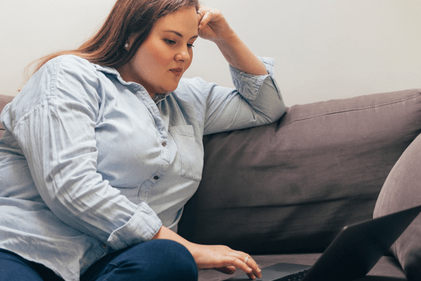 Person using a laptop while seated on a couch at home 
