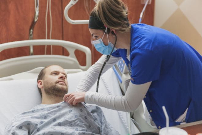 A nurse checks the heartbeat of a hospitalized patient