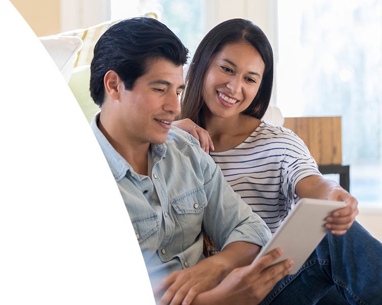 Couple sitting together at home looking at a tablet and reviewing information.