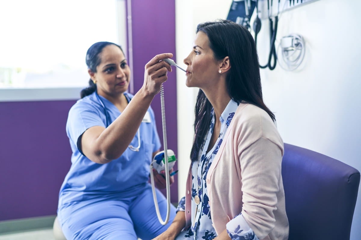 A nurse examines a patient in an examination room.