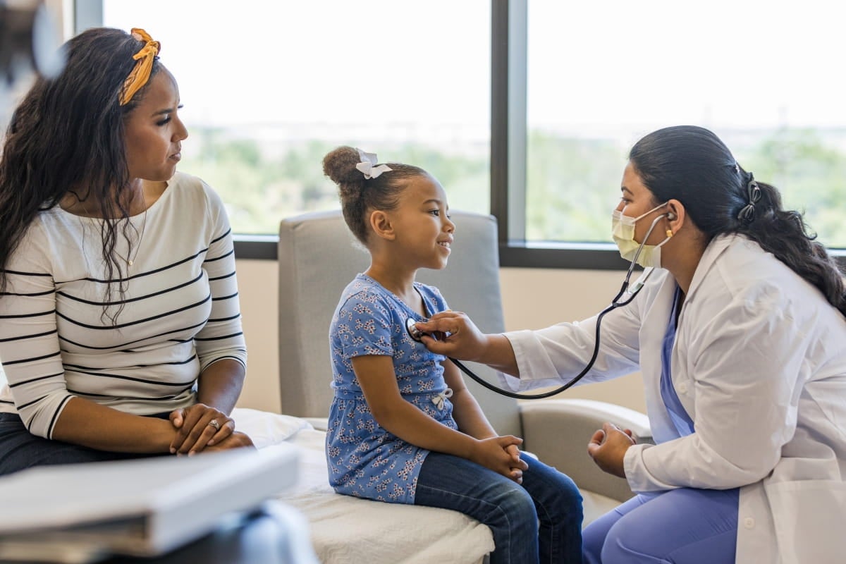 A nurse examines a child patient in an examination room.
