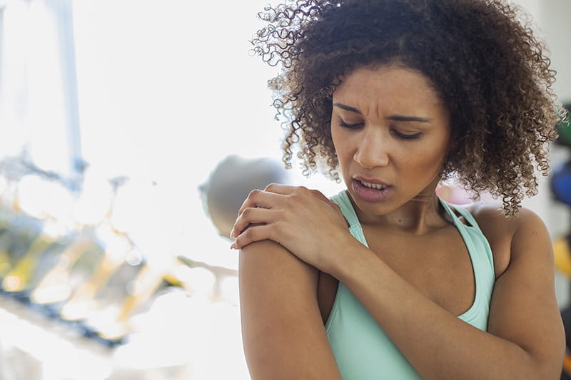 Woman holding her shoulder in pain