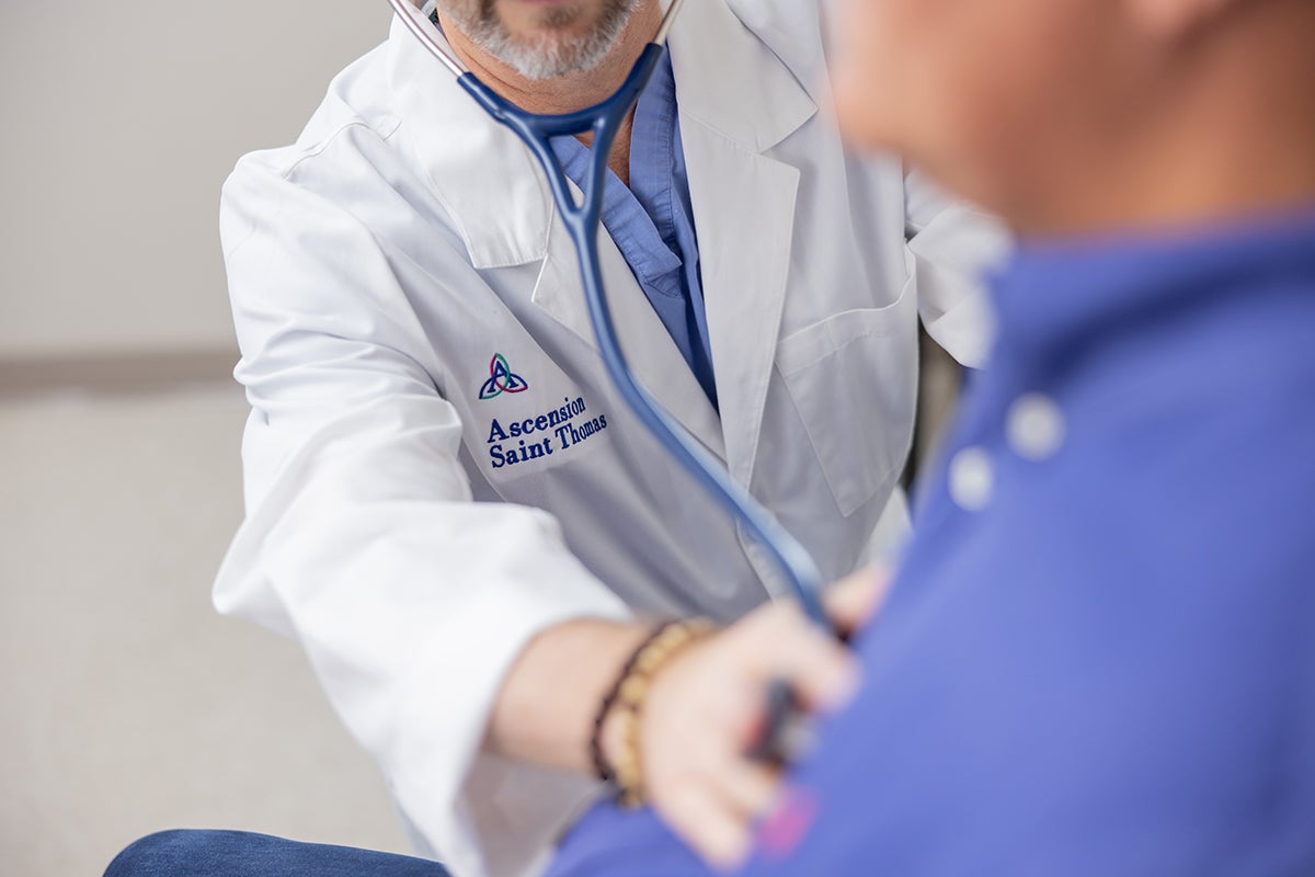 An Ascension Saint Thomas physician places a stethoscope on a patient's chest to listen to his heartbeat. 