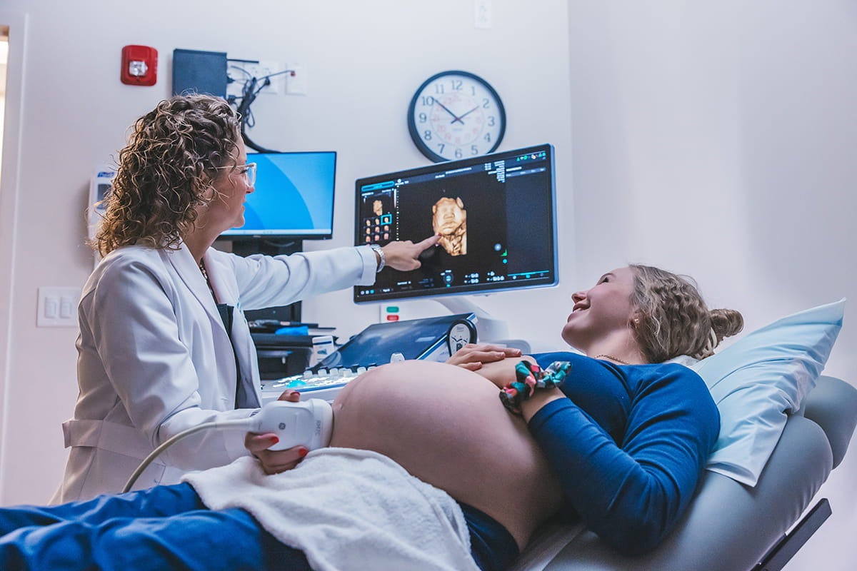 A technician is performing an ultrasound on a pregnant patient.