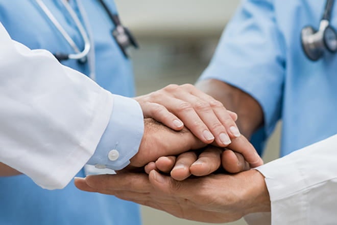 Doctors and surgeons showing teamwork by holding hands.
