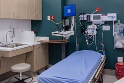 Private emergency treatment room with stretcher, patient monitor, exam light and medical equipment.