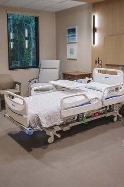 Private inpatient rehabilitation room at Ascension Sacred Heart featuring an adjustable hospital bed, family seating, bedside table, and large window designed for comfort during recovery.