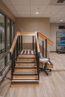 Rehabilitation therapy staircase with handrails on both sides for practicing stair climbing, balance, and safe mobility during physical therapy.