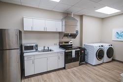 Fully equipped therapy kitchen and laundry room where patients practice cooking, household tasks, and independent living skills as part of rehabilitation.