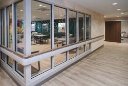 Bright rehabilitation hallway with handrails and views into therapy spaces, supporting safe walking practice and mobility training.
