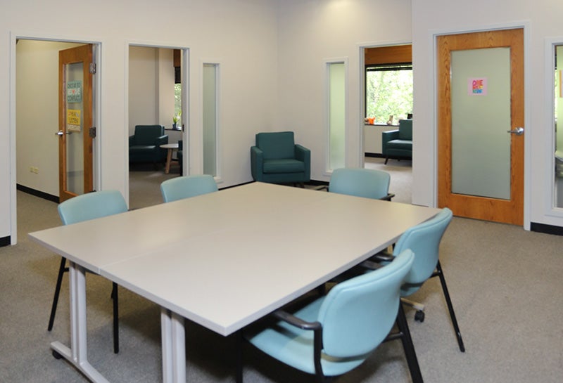 Meeting room with table and chairs, adjacent to private consultation rooms with seating.