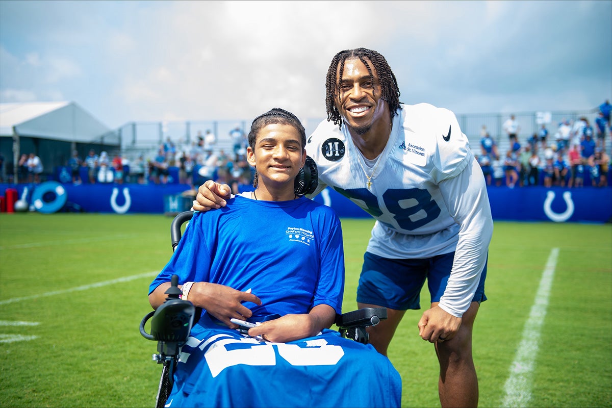 Indianapolis Colts player poses with a child in a wheelchair during a hospital community event